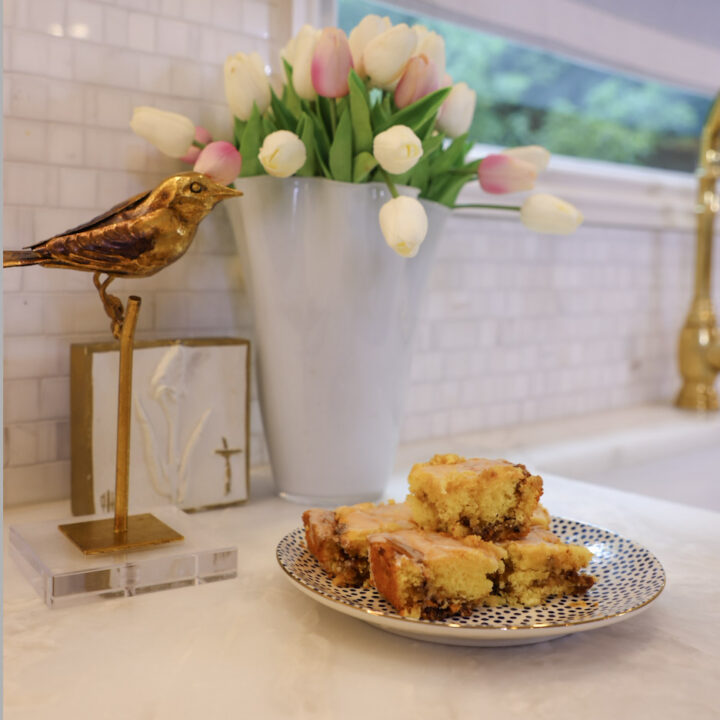 Squares of Family Savvy's Honey Bun Cake sitting on a plate on a marble kitchen counter