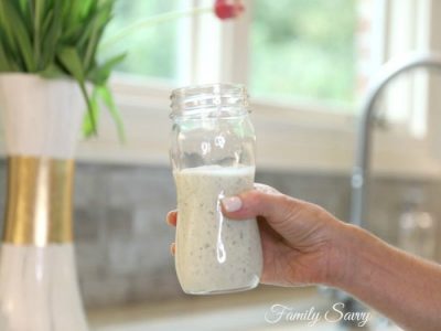 Close-up of a hand holding a jar of Family Savvy's Chuy's Creamy Jalapeno Dip Copycat Recipe