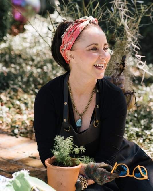 Ally Phillips, a food influencer, sitting in a green garden wearing a black blouse with a red headband