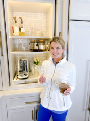 Jamie Tarence, founder of Family Savvy, holding JoyJolt mugs in front of her coffee bar
