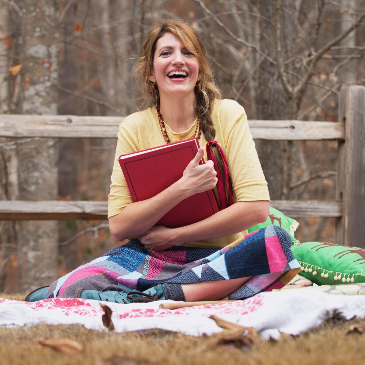Amy Grimes of Story Paintings sitting on a blanket outside with a red book