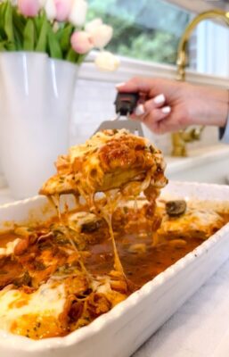 Mozzarella & Pepperoni Chicken being lifted from a white casserole dish with melted cheese stretching and rich tomato sauce — Family Savvy