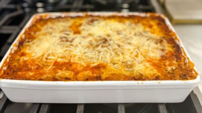Hot spaghetti pie recipe with melted cheese on top in a white casserole dish