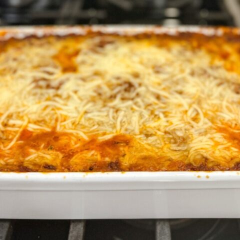 Hot spaghetti pie recipe with melted cheese on top in a white casserole dish