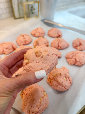 Close up of a woman's hand holding a strawberry white chocolate chip cookie