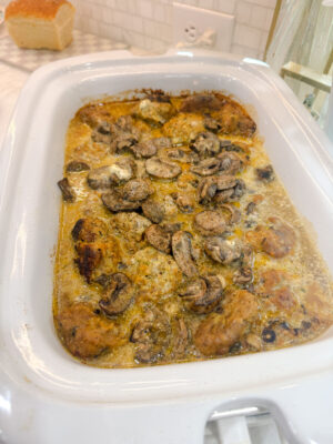 Swedish meatballs cooking in a mushroom sauce in a casserole-style slow cooker