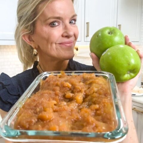 Close up of Jamie Tarence of Family Savvy holding a glass container of cinnamon apples and a handful of green Granny Smith apples