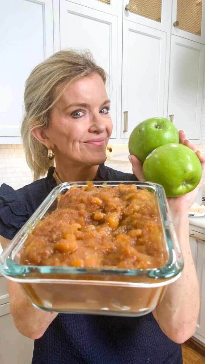 Close up of Jamie Tarence of Family Savvy holding a glass container of cinnamon apples and a handful of green Granny Smith apples