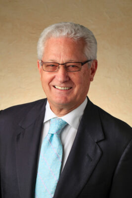 Headshot of David Green, CEO and Founder of Hobby Lobby, wearing a suit with a blue tie