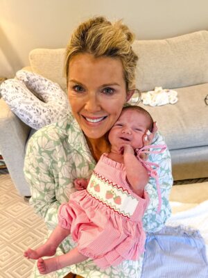 Jamie Tarence of Family Savvy holding her granddaughter Anne Parker, who is wearing a red and white strawberry bubble gown from Stitchy Fish