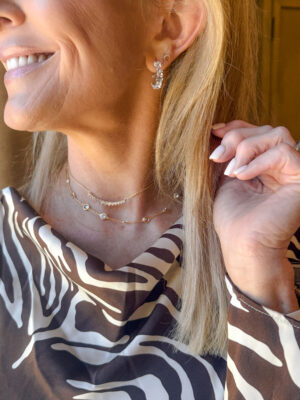 Close-up of Jamie Tarence of Family Savvy wearing Dorsey's Gold Clemence Necklace, Aurate's Curve Silver Necklace & Aurate's Lab Grown White Sapphire Mixed Shape Hoop Earrings