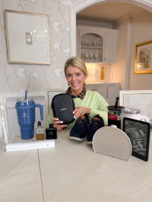 Jamie Tarence of Family Savvy holding a variety of items on her Men's Gift Guide