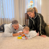 Jamie Tarence of Family Savvy sitting on the floor with her husband Zane and granddaughter Anne Parker