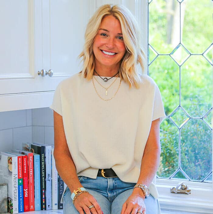 Deanna Pizitz of Well and Worthy Life sitting on her kitchen counter near a window