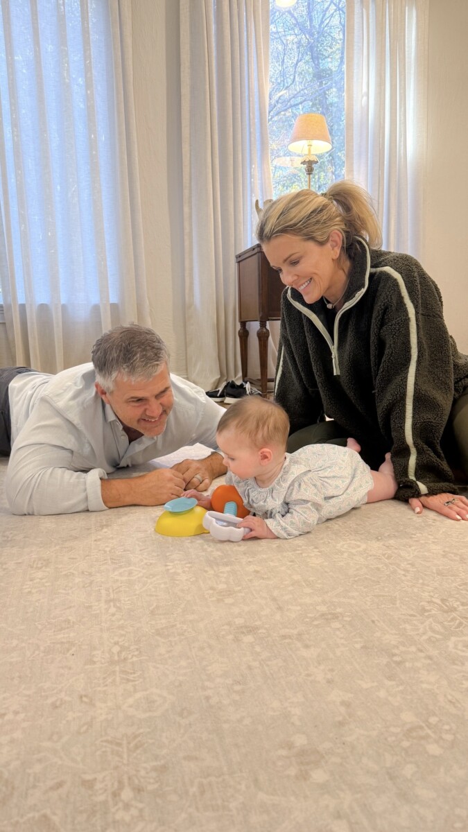 Jamie and Zane Tarence playing with their baby granddaughter Anne Parker on their light living room carpet