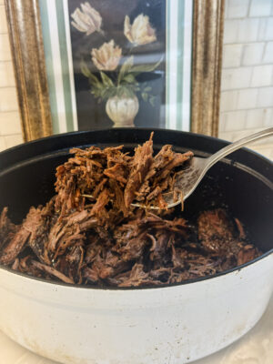 A fork full of tender rump roast hovering over a Dutch oven