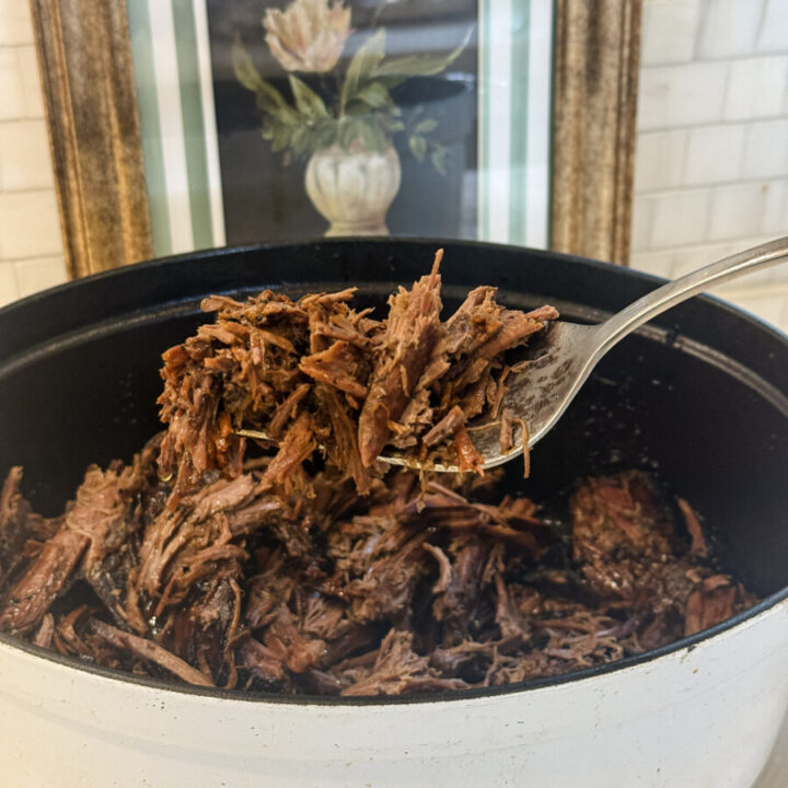 A fork full of tender rump roast hovering over a Dutch oven