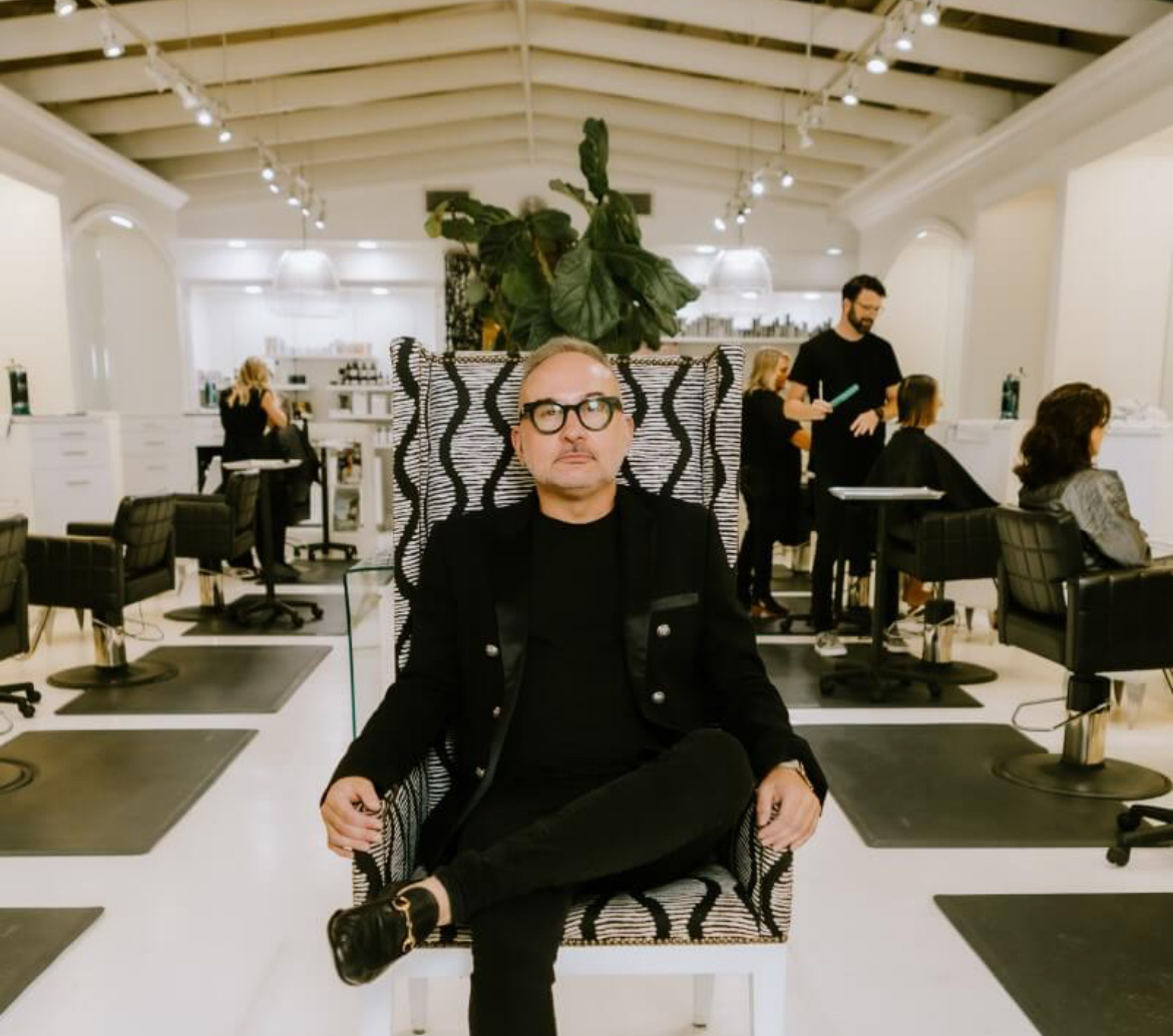 Chris Presley, hairstylist and owner of Fringe Soho salon, posing in a chair in the middle of the salon