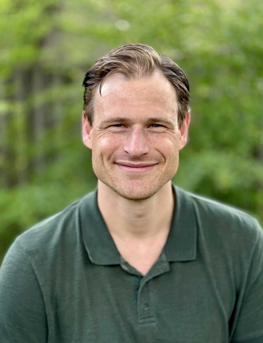 Mental health counselor Tyler Palmquist sitting outdoors and smiling.